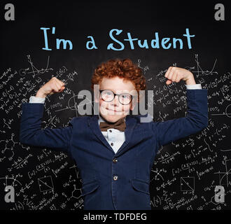 Kleines Kind Student. Smart redhead Kid in Anzug und Brille auf der Tafel Hintergrund mit Wissenschaft Formeln Stockfoto