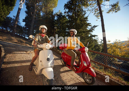 Glückliches junges Paar in Liebe auf Roller zusammen fahren. Stockfoto