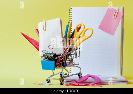 Warenkorb mit unterschiedlichen Schreibwaren auf dem gelben Hintergrund. Stockfoto
