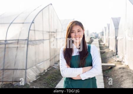 Junge schöne asiatische Frau arbeitet im grünen Feld Stockfoto