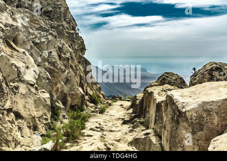 Steinigen weg im Hochland am sonnigen Tag. Klar lue Sky und einige Wolken am Horizont. Rocky tracking Straße in trockenen Berggebiet. Süden von Teneriffa. Stockfoto