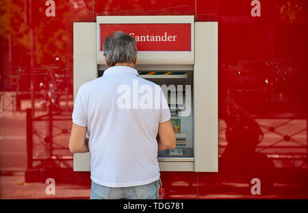 Ein Kunde zieht Geld aus einem Geldautomaten am Spanischen multinationale kommerzielle Bank- und Finanzdienstleistungen Santander in Spanien. Stockfoto