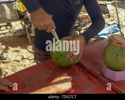 Ein Anbieter öffnet einen grünen Kokosnuss am Strand von Copacabana, Rio de Janeiro Stockfoto