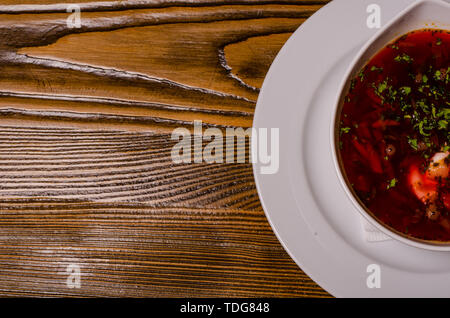 Beats Suppe, borschtsch mit Sauerrahm; Raupe und Pickles auf einem Hintergrund. borsch in einem weissen Teller, Brot auf einem hölzernen Schneidebrett, ganze Pickles Stockfoto