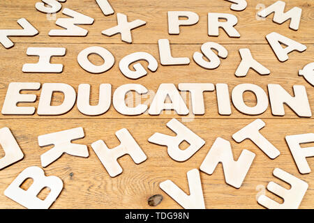 Wort Bildung ist aus Holz Buchstaben in der Mitte der verschiedenen Buchstaben zufällig auf einen hölzernen Tisch verstreut festgelegt Stockfoto