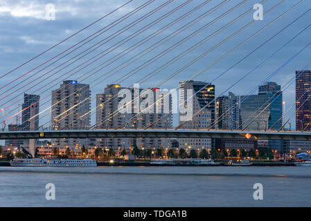 Rotterdam, Niederlande - 5. Mai 2019: Erasmus Brücke und die Neue Maas mit Hochhaus im Hintergrund in der Dämmerung Stockfoto