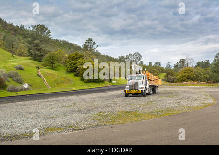 Kalifornien, USA, 4. April 2019: Big Truck mit Überbreite unterzeichnen und Step down Trailer transportieren und für den Transport von Holz. Stockfoto