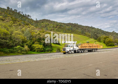 Kalifornien, USA, 4. April 2019: Big Truck mit Überbreite unterzeichnen und Step down Trailer transportieren und für den Transport von Holz. Stockfoto