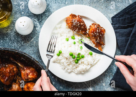 Gebratene Teriyaki Hähnchen Schenkel mit Reis und Erbsen auf weiße Platte. Tabelle Ansicht von Oben. Leckeres Abendessen essen Stockfoto