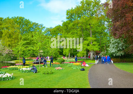 Keukenhof, Lisse, Niederlande - Apr 28 2019: Menschen zu Fuß in der schönen Gartenanlage Keukenhof. Beliebte touristische Park mit grünen Bäumen und bunten Blumen, vor allem Tulpen. Großen Niederländischen touristische Attraktion. Stockfoto