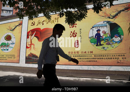 Peking, China. 14 Juni, 2019. Ein Mann hinter einem Propaganda banner beschreiben die Werte der Chinesischen Kommunistischen Partei an den Straßen in Peking. Quelle: Andrea Verdelli/SOPA Images/ZUMA Draht/Alamy leben Nachrichten Stockfoto