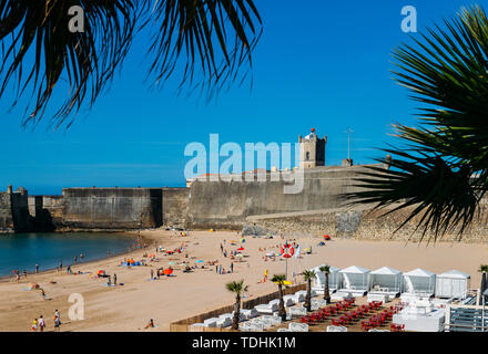 Estoril, Portugal - 10. Juni 2019: Frame von Fort in Torre Strand, blauer Himmel und Ozean Wellen, gelb braun Sand, Menschen zu Fuß im Sand Stockfoto