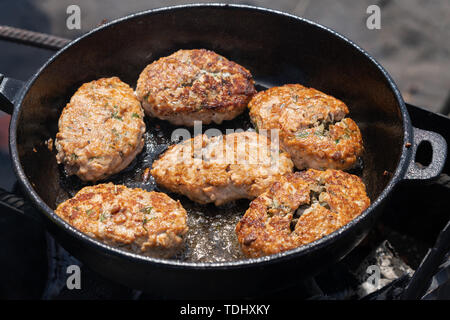 Köstliche Wild Rot Lachs Fisch knusprige Schnitzel gebraten in heißen Bratpfanne braten auf Kohlen, über offenem Feuer am Lagerfeuer. Kochen auf Feuer beim Picknick auf s Stockfoto