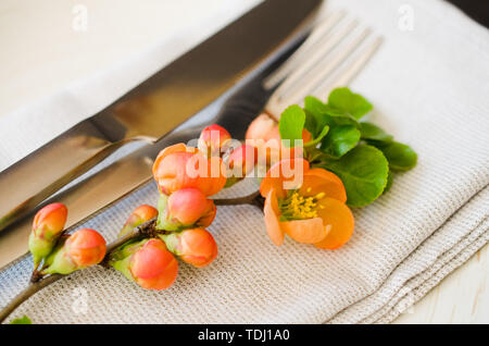 Jahrgang Tabelle mit zarten Blüten auf einer Leinwand Serviette auf einem dunklen Hintergrund, close-up. Urlaub Tabelle mit floralem Dekor Stockfoto