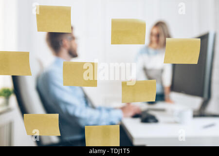 Geschäftsleute im Büro hinter einer Glaswand arbeiten Stockfoto