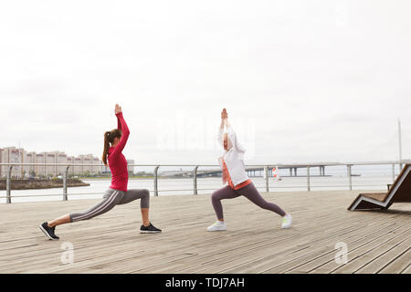 Seitenansicht Porträt zweier Frauen Yoga auf Pier in Morgen, kopieren Raum Stockfoto