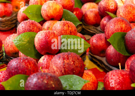 Frische rote Äpfel mit grünen Blättern und Wassertropfen im Markt. Stockfoto