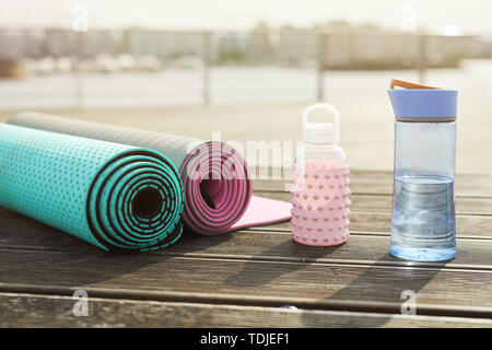 Hintergrundbild von Yoga Matten und Wasserflaschen für Workout auf hölzernen Pier im Freien, kopieren Raum Stockfoto