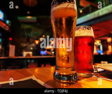 Gläser der hellen und dunklen Bier in einem Pub Hintergrund. Atmosphärische Dämmerungseinstellung in der Bar. Foto Stockfoto