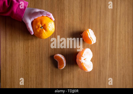 Baby s Hand manipulieren von verschiedenen Früchten auf einem Holztisch Stockfoto