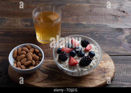 Gesundes Frühstück Müsli mit Erdbeeren, Blaubeeren, Brombeeren, Mandeln und Haselnüsse mit Trockenfrüchten Kompott. Stockfoto