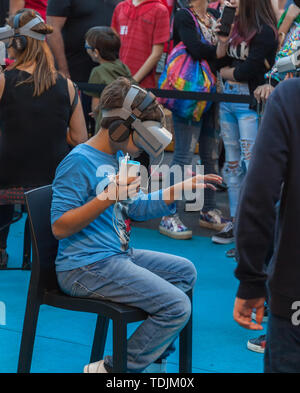 Ein Junge und ein Mädchen die Möglichkeiten von virtual reality Brillen an einer Ausstellung, auf santelmo Avenue, Buenos Aires, Argentinien. 15. Mai 2019. Stockfoto