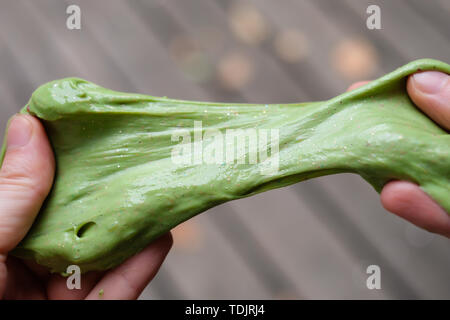 Grüne Anti stress toy Schleim mit Glitzer in den Händen. Kampf gegen Angst und Stress. Kreative Spiel experimentieren für Kinder. Stockfoto