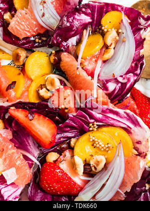 Radicchio Salat mit Regenbogen Karotten, Beeren, Früchten und Haselnüsse in Weiß Tablett serviert. Stockfoto