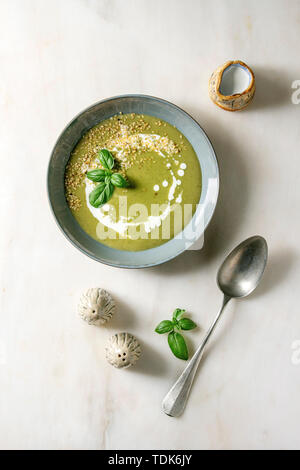 Grünes Gemüse Suppe Spargel, Brokkoli oder Erbse, von Basil eingerichtet, Sesamsamen, Creme in Keramik Schüssel mit Salz und Pfeffer, Krug von Creme über Weiß Stockfoto