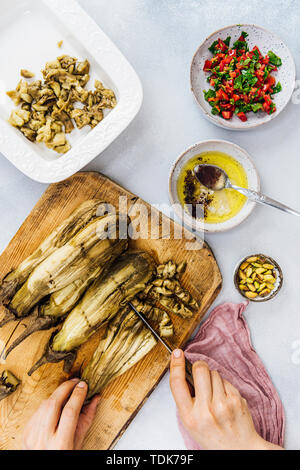 Frau hacken geröstete Auberginen auf einem Holzbrett türkische Auberginen Salat zu machen Stockfoto