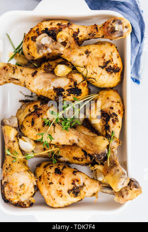 Ofen gebackene Hähnchenschenkel mit Kräutern und Knoblauch in eine Backform aus Sicht von oben fotografiert. Stockfoto