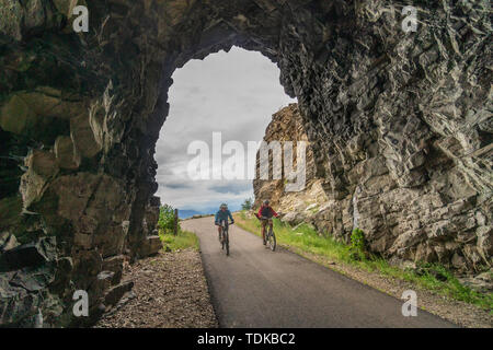 Paar Radfahren in einem der Tunnel der Kettle Valley Railway (KVR) eine verlassene Eisenbahn zu einem Wander-/Radweg umgewandelt. Stockfoto