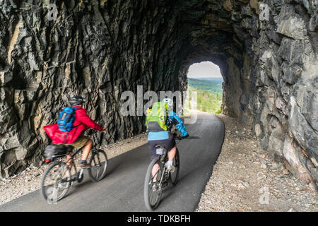 Paar Radfahren in einem der Tunnel der Kettle Valley Railway (KVR) eine verlassene Eisenbahn zu einem Wander-/Radweg umgewandelt. Stockfoto