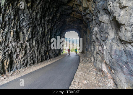 Paar Radfahren in einem der Tunnel der Kettle Valley Railway (KVR) eine verlassene Eisenbahn zu einem Wander-/Radweg umgewandelt. Stockfoto