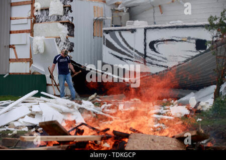 Ellettsville, Indiana, USA. 16 Juni, 2019. Brennenden Rückständen auf ein beschädigtes Gebäude in Flatwoods Straße, während die Folgen. Ein Tornado schlug den Bereich verlassen ein Patch der Beschädigung von Greene County, Monroe County im Norden zu zerstören, Bäume, Häuser, Autos, und aus ein Pfad von Schmutz und die Linien auf dem Boden. Credit: SOPA Images Limited/Alamy leben Nachrichten Stockfoto