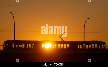 Magdeburg, Deutschland. Juni, 2019 18. Eine Straßenbahn überquert eine Brücke bei Sonnenaufgang und bringt die ersten Pendler in die Innenstadt. Die Region rund um die Landeshauptstadt ist mit einem warmen, sonnigen Sommertag. Am späten Nachmittag sollte die Temperatur über 30 Grad Celsius liegen. Credit: Klaus-Dietmar Gabbert/dpa-Zentralbild/ZB/dpa/Alamy leben Nachrichten Stockfoto