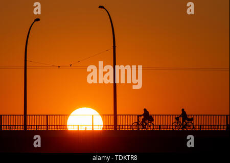 Magdeburg, Deutschland. Juni, 2019 18. Radfahrer überqueren Sie eine Brücke bei Sonnenaufgang. Die Region rund um die Landeshauptstadt ist mit einem warmen, sonnigen Sommertag. Am späten Nachmittag sollte die Temperatur über 30 Grad Celsius liegen. Credit: Klaus-Dietmar Gabbert/dpa-Zentralbild/ZB/dpa/Alamy leben Nachrichten Stockfoto