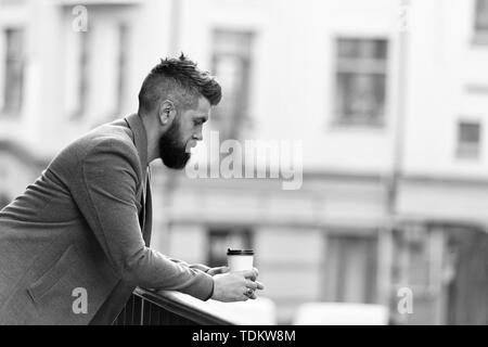 Stadt Lebensstil. Geschäftsmann gepflegt aussehen genießen Sie Kaffee Pause aus Business Center im städtischen Hintergrund. Entspannen und erholen Sie sich. Man bärtige hipster Kaffee trinken Pappbecher. Noch ein Schluck Kaffee. Stockfoto