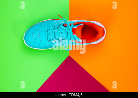 Rot, Hellblau, Weiß neu Tennisschuh im Studio Schuß über grün, orange, lila Hintergrund. Direkt von oben. Stockfoto