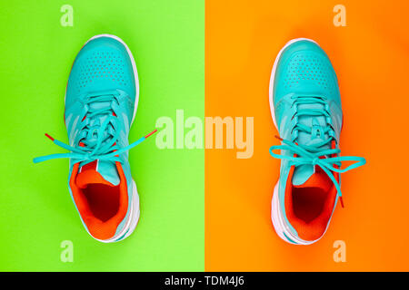 Rot, hellblau, weiß, Paar neue Tennisschuhe im Studio Schuß über grün, orange Hintergrund. Direkt von oben. Stockfoto
