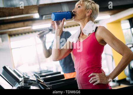 Reife Frau Trinkwasser in der Turnhalle nach dem Workout Stockfoto
