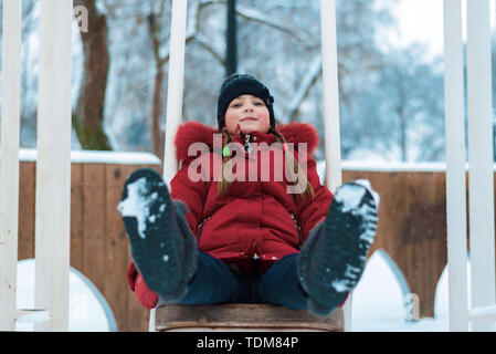 Kleines Mädchen im Winter Fahrt auf einer Schaukel Stockfoto