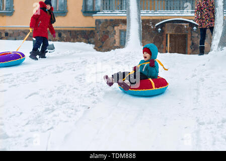 Glückliches Kind. kleiner Junge im Winter Fahrt auf einem Schlitten aus dem Berg. Kind lange und glückliche Lächeln und Spaß zu haben. Stockfoto