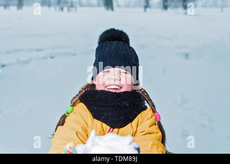 Kleines Mädchen mit Zöpfen lächelnd. glückliches Kind heraus halten den Schnee. winter Portrait von glückliches Kind Stockfoto