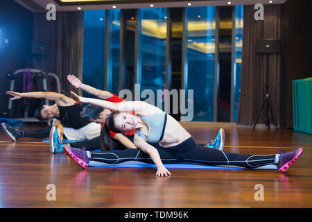 Jungen asiatischen Menschen, die Yoga im modernen Fitnessraum Stockfoto