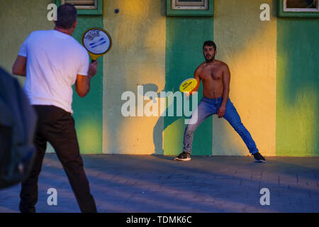 Zwei junge Männer spielen mit einem Paddel und gummi ball AKA Matkot am Strand. Am Strand fotografiert, Tel Aviv, Israel bei Sonnenuntergang Stockfoto