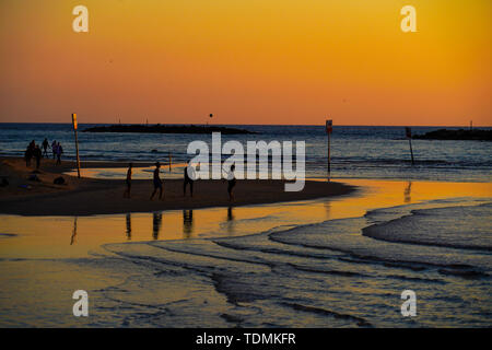 Silhouette von Menschen am Strand bei Sonnenuntergang. Am Strand von Tel Aviv, Israel im März fotografiert. Stockfoto