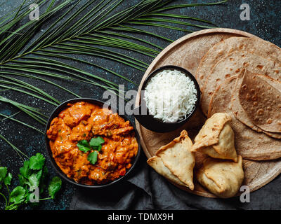 Indische Küche Gerichte: Tikka Masala, Reis, Samosa, chapati,. Indische Küche auf dunklem Hintergrund mit kopieren. Sortiment indisches Essen Top View oder flach. Stockfoto