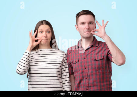 Junge mute Paar hält Finger auf die Lippen wie Reißverschluss geheime Verschwörung zu halten Stockfoto