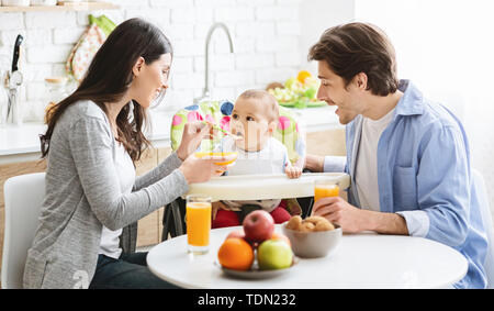 Gut aussehende junge Familie Frühstück zusammen essen mit Ihrem Baby Stockfoto